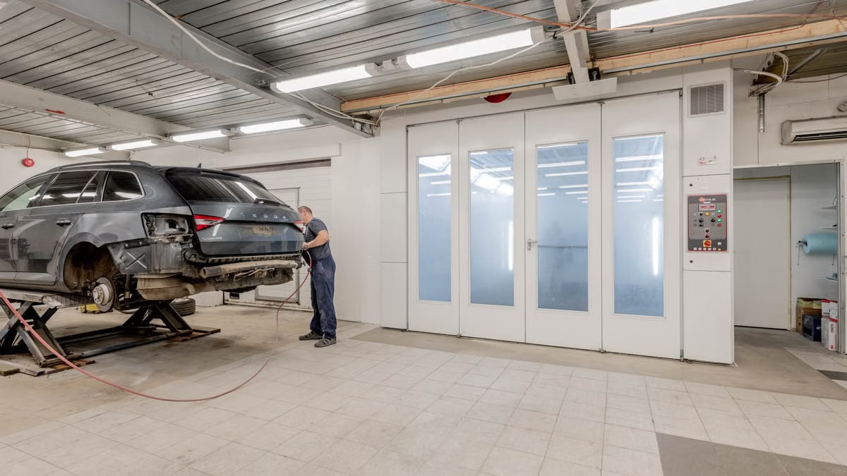Mechanic repairing a car indoors at an auto workshop, focusing on vehicle maintenance.